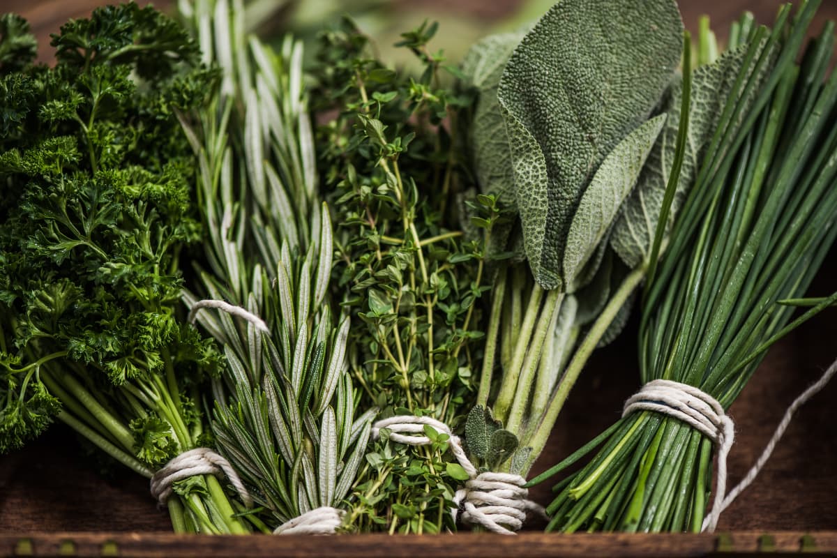Fresh herbs on a wooden cutting board in a clean kitchen — simple kitchen tools that reduce cooking effort